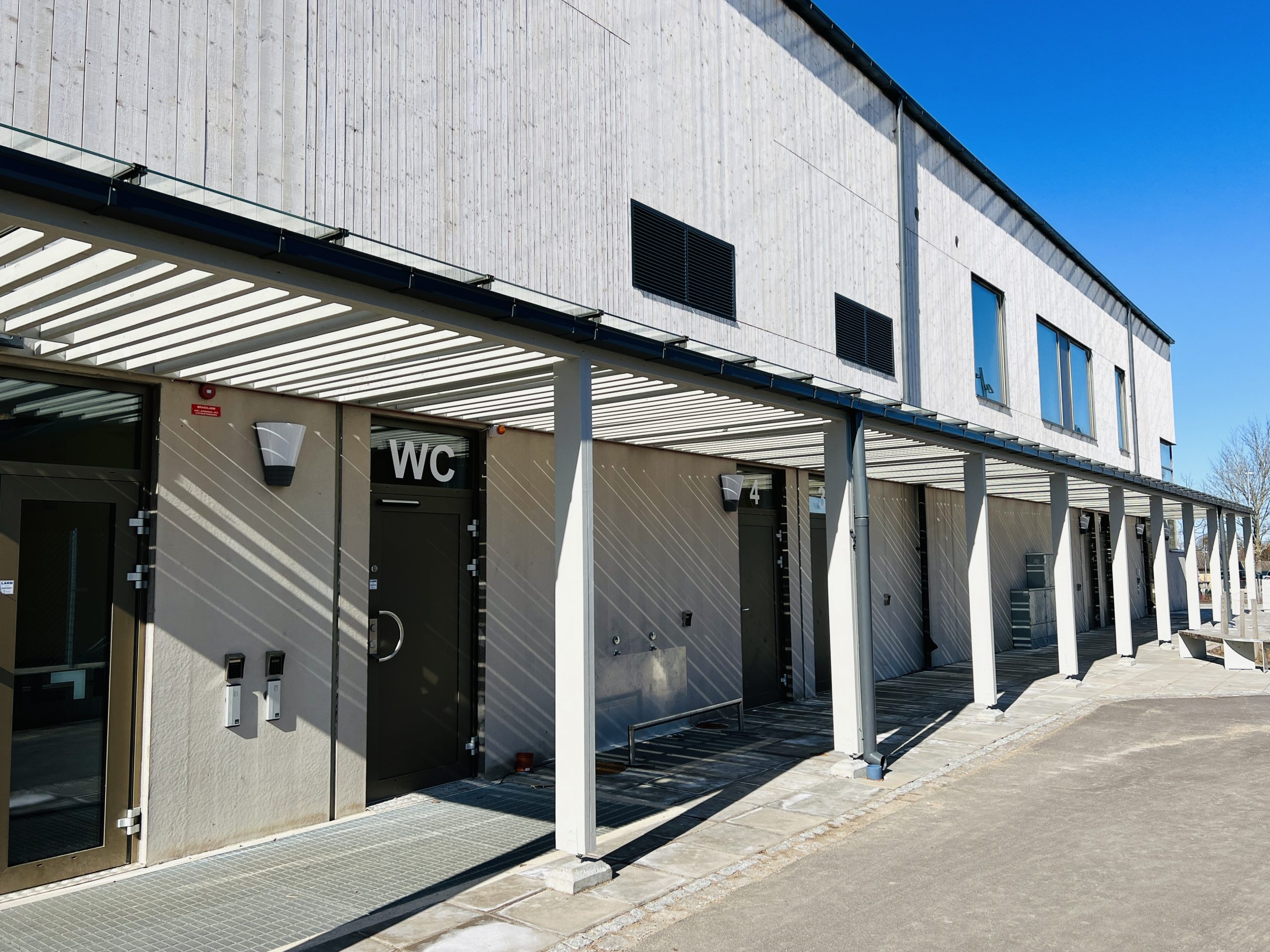 Nybyggnad av Gantofta Idrottshall sett utifrån modern betongbyggnad med inslag av trä och stora fönsterytor