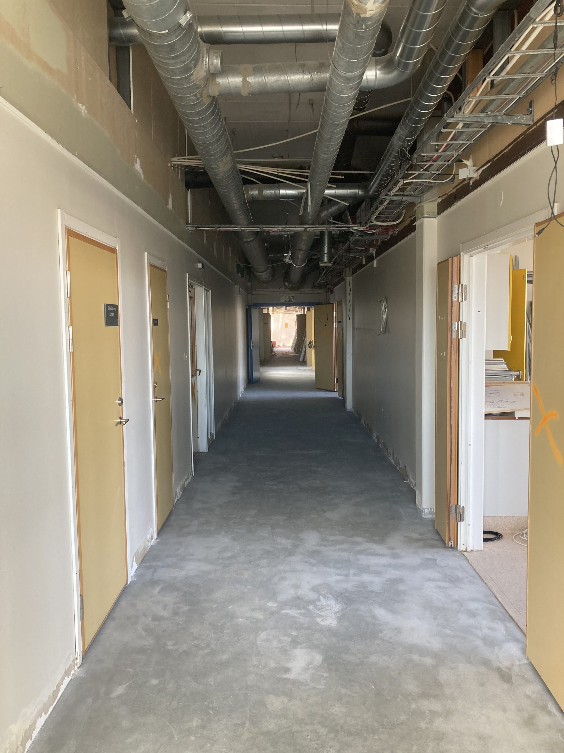Rivningsbilder från projektet, här en tråkig korridor med gamla gula dörrar
