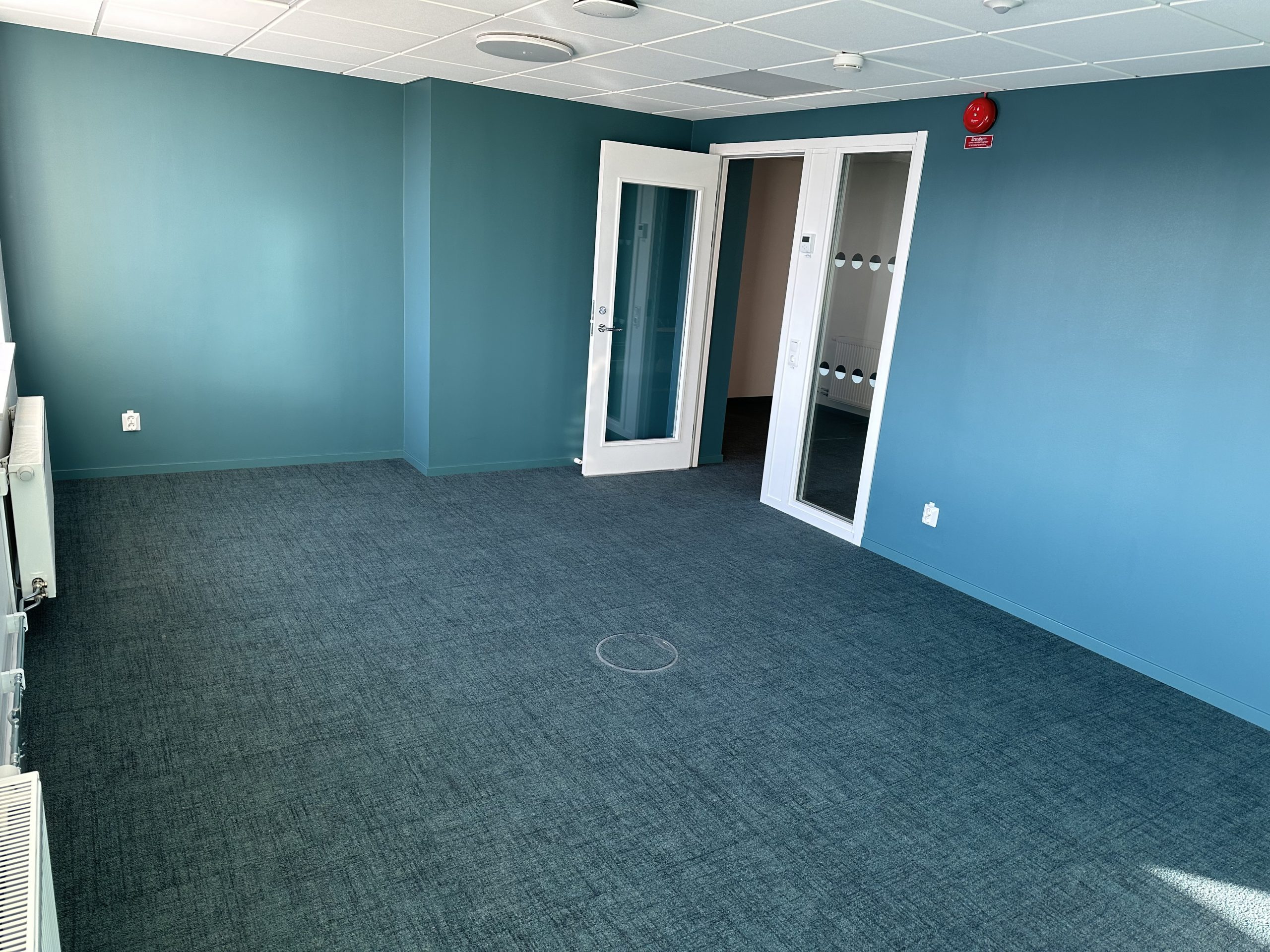 Ett av rummen med nya golvmattor i grått och härlig grön/blå färg på väggarna