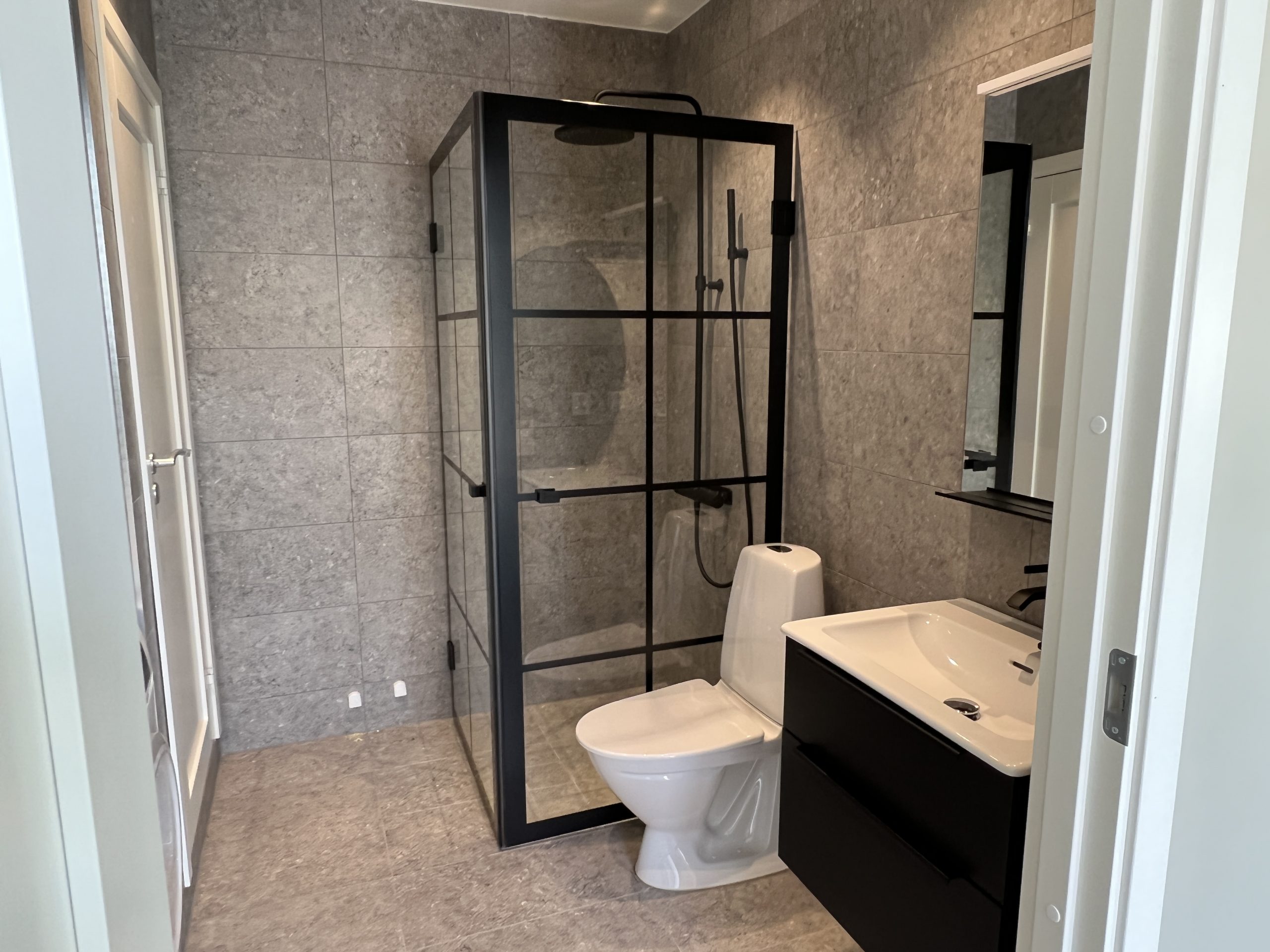 snyggt och stiligt badrum med duschväggar i svart ram