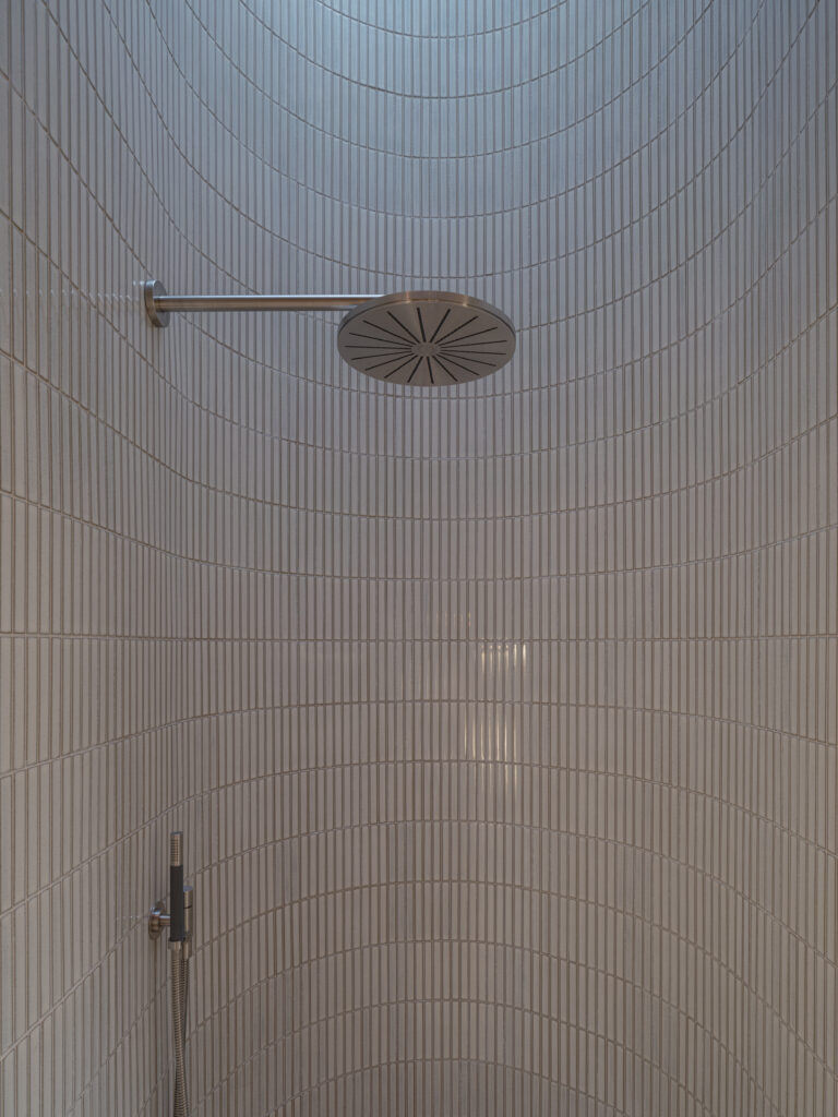 Exklusivt badrum i Villa P2 med väggar och inredning i trä och sten, stort fönster och takfönster i duschen som släpper in naturligt ljus. Harmonisk design med noggrant utvalda material och tidlös elegans.