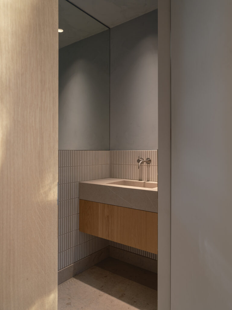 Exklusivt badrum i Villa P2 med väggar och inredning i trä och sten, stort fönster och takfönster i duschen som släpper in naturligt ljus. Harmonisk design med noggrant utvalda material och tidlös elegans.