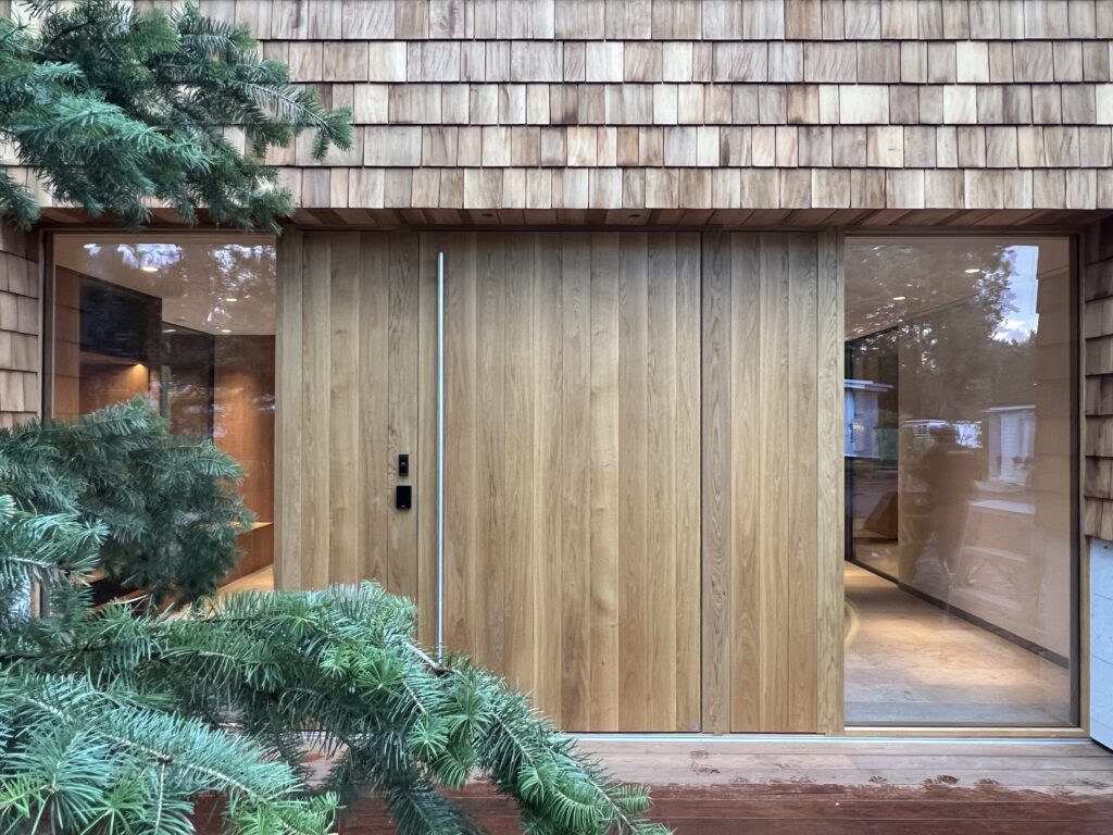 Exteriör av Villa P2 i Höllviken – en arkitektritad villa från Sawi Exclusive Homes by Treano, omgiven av tallar och ljung. Den moderna fasaden, harmonisk belysning och naturliga material framhäver husets exklusiva design och miljöklassificering 1.0.