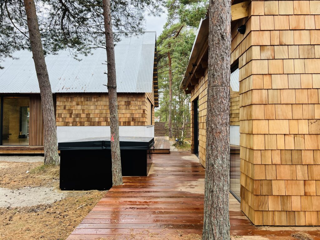 Exteriör av Villa P2 i Höllviken – en arkitektritad villa från Sawi Exclusive Homes by Treano, omgiven av tallar och ljung. Den moderna fasaden, harmonisk belysning och naturliga material framhäver husets exklusiva design och miljöklassificering 1.0.