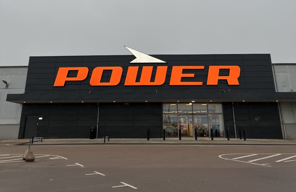 Bilderna visar både utsidan och insidan av en Power-butik. Utomhus syns den stora grå fasaden med den orangea Power-logotypen, ibland med avspärrningar uppställda framför entrén och ibland en tom parkering. Inomhus visas butikens elektronikavdelning med hyllor av produkter, kampanjskyltar och dekorationer i svart och orange